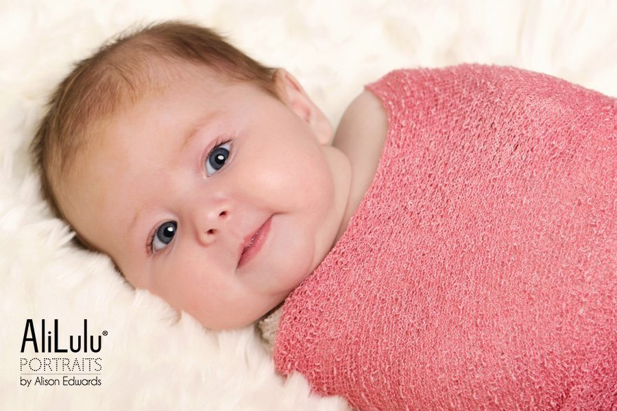 baby girl with eyes open wearing coral pink wrap